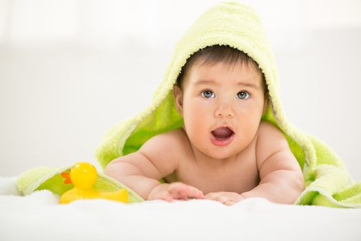 Cute baby boy lying under a towel