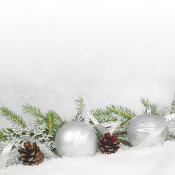 Christmas balls, pine cones and green fir branch on snow