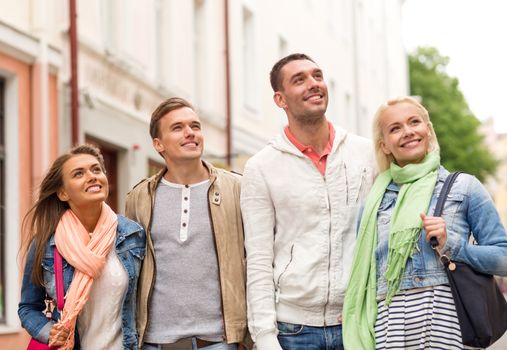 friendship, travel and vacation concept - group of smiling friends walking in the city