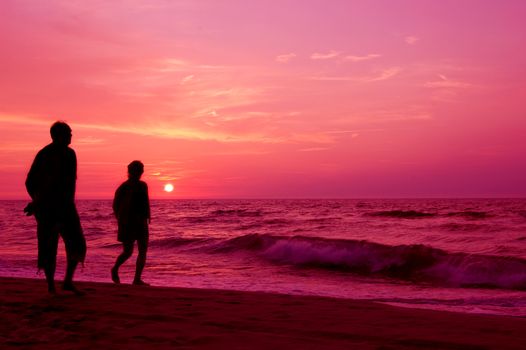 Active. Couple walking on the beach at sundown.