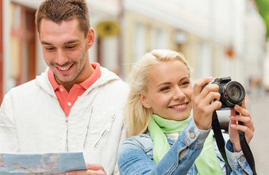 travel, vacation, technology and friendship concept - smiling couple with map and photocamera exploring city