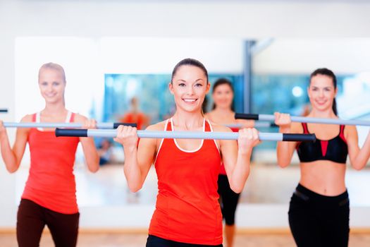 fitness, sport, training, gym and lifestyle concept - group of smiling people working out with barbells in the gym