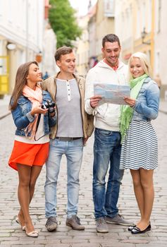 travel, vacation, technology and friendship concept - group of smiling friends with map and photocamera exploring city