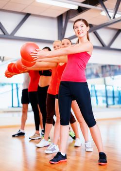 fitness, sport, training, gym and lifestyle concept - group of smiling people working out with stability balls in the gym