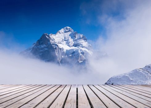 snow peaks of Jungfrau region grindelwald switzerland with wooden terrace