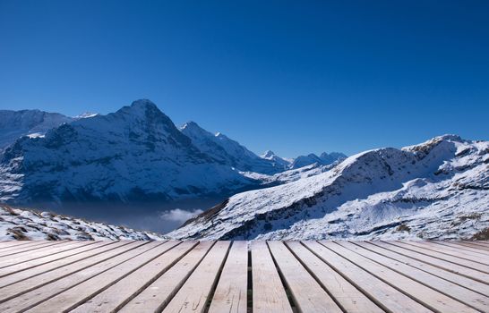 snow peaks of Jungfrau region grindelwald switzerland with wooden terrace