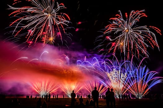 Colorful fireworks of various colors over night sky with spectators