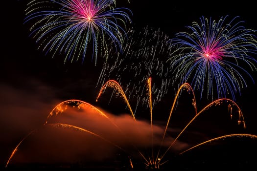 Colorful fireworks of various colors over night sky with spectators