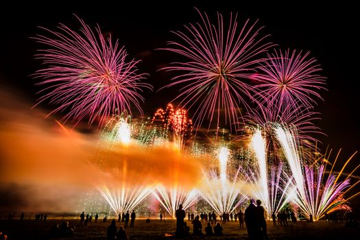 Colorful fireworks of various colors over night sky with spectators