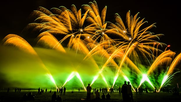 Colorful fireworks of various colors over night sky with spectators