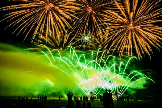 Colorful fireworks of various colors over night sky with spectators