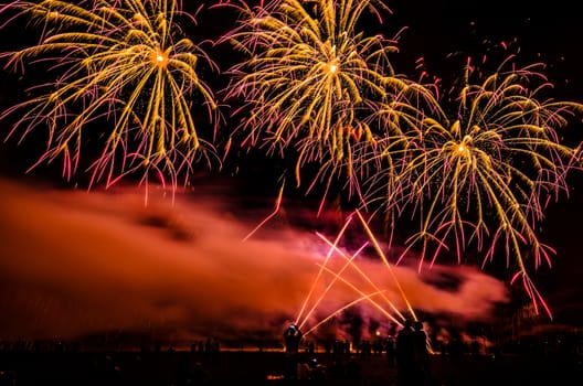 Colorful fireworks of various colors over night sky with spectators