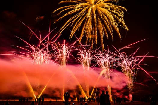 Colorful fireworks of various colors over night sky with spectators