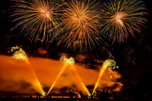 Colorful fireworks of various colors over night sky with spectators