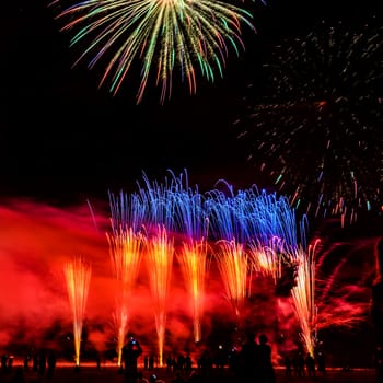 Colorful fireworks of various colors over night sky with spectators