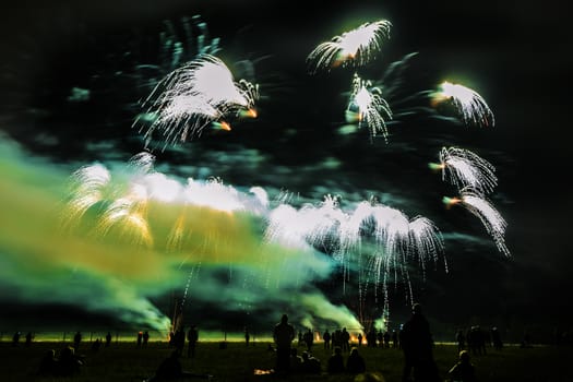 Colorful fireworks of various colors over night sky with spectators