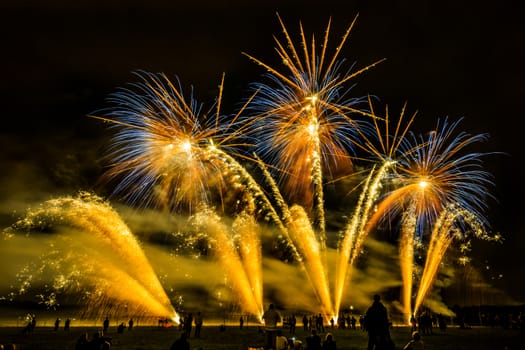 Colorful fireworks of various colors over night sky with spectators