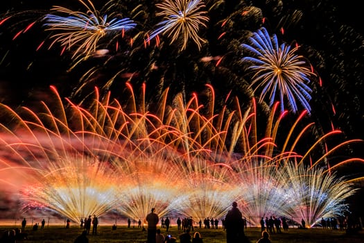 Colorful fireworks of various colors over night sky with spectators