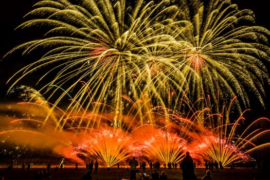 Colorful fireworks of various colors over night sky with spectators