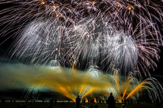 Colorful fireworks of various colors over night sky with spectators