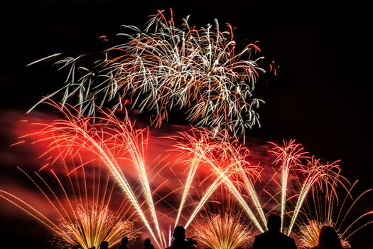 Colorful fireworks of various colors over night sky with spectators