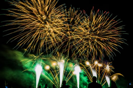 Colorful fireworks of various colors over night sky with spectators