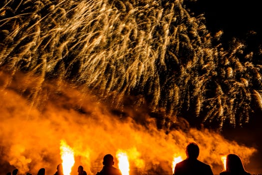 Colorful fireworks of various colors over night sky with spectators