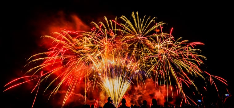 Colorful fireworks of various colors over night sky with spectators