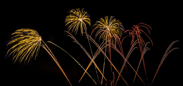 Colorful fireworks of various colors over night sky with spectators