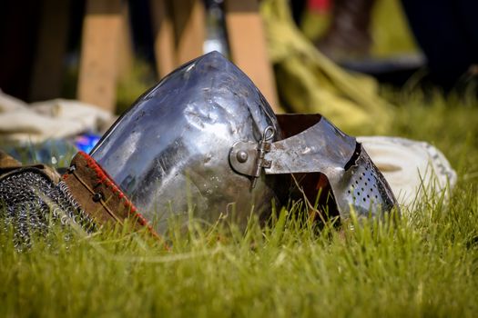 Helmet of the medieval knight on the green field.