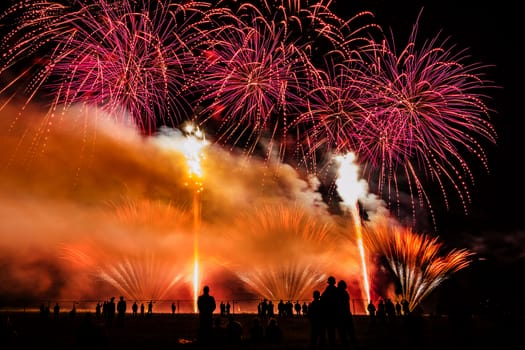 Colorful fireworks of various colors over night sky with spectators