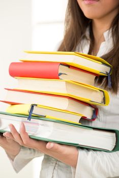 Unknown beautiful teenage girl holding many Colorful books 