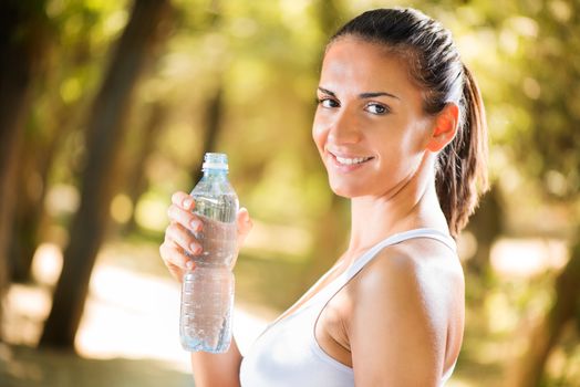 Happy young beautiful woman with water bottle  in the nature