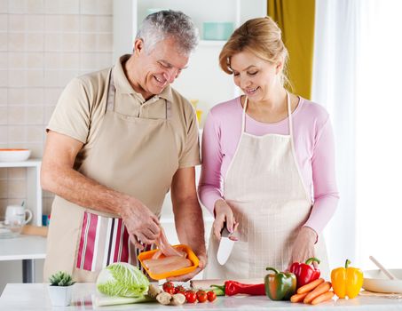 Happy Senior Couple preparing food in the kitchen.