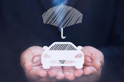 Business man holding a car icon protected by an umbrella 