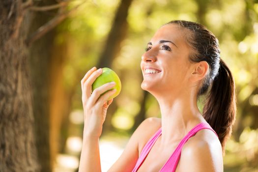 Happy young beautiful woman with apple in the nature