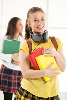 Happy beautiful teenage girl with Colorful books and school bag