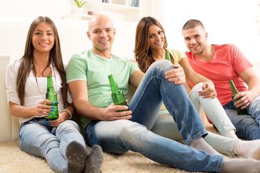 Four friends enjoying with beer together at the home party.