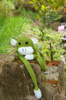 Abstract knitted monkey, symbol of year 2016, handmade toy from yarn, she lie down or sit lonely among nature, happy new year 2016, year of the monkey