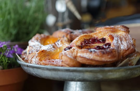 Delicious fruit pastries dusted with icing sugar powder on a rustic metal plate