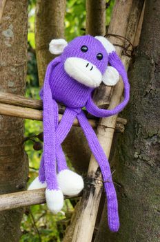 Abstract knitted monkey, symbol of year 2016, handmade toy from yarn, she lie down or sit lonely among nature, happy new year 2016, year of the monkey
