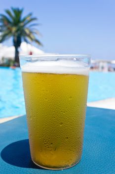 A glass of cold beer by the pool