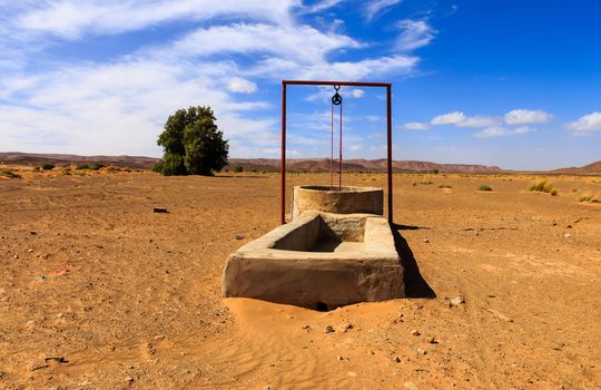 water well in the Sahara desert and the passing caravan