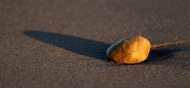 Stone at the beach in sand through sunset time.