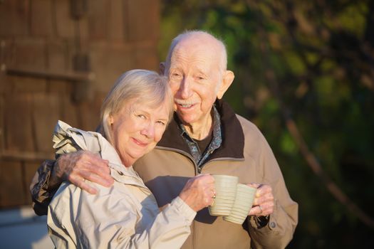 Cute couple standing outdoors holding coffee mugs