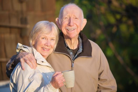 Confident white senior citizen couple outdoors with coffee