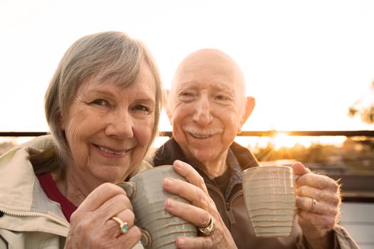 Cheerful older couple sitting outdoors with coffee
