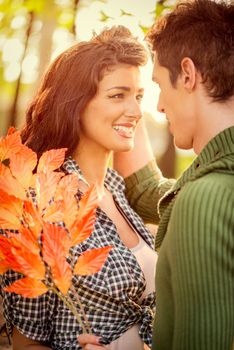 Close-up pretty girl and guy who are embracing, looking at each other, while the setting sun shines.