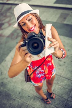 Beautiful young woman photographing with digital camera