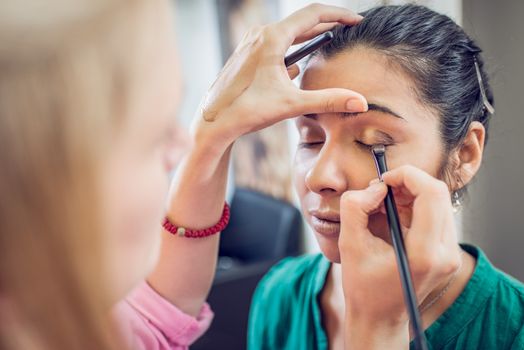 Make-up artist applying the eyeshadow to model. Close up. 